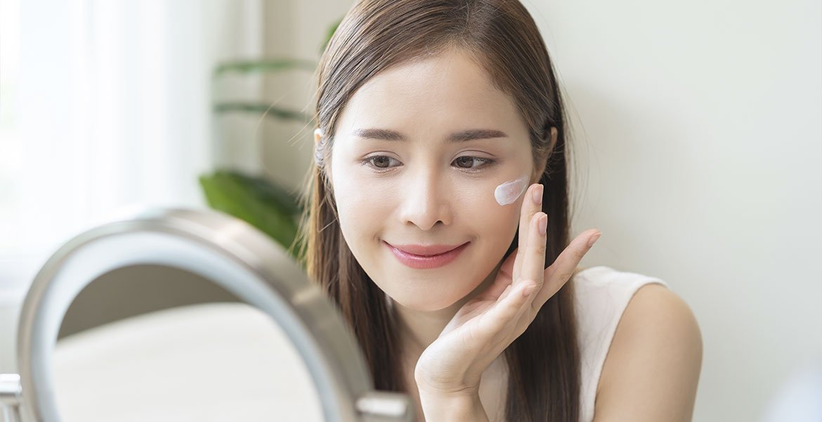 Garota com glass skin massageia a pele do rosto com creme para uma pele mais luminosa